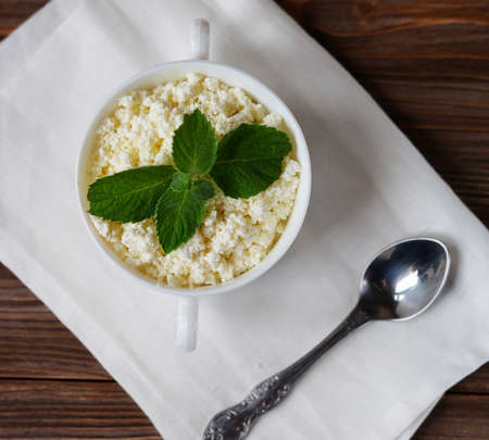 good breakfast. Cottage cheese with mint in a white bowl on a white napkin. flat lay. top view.