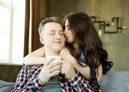 Lifestyle, family and people concept: young beautiful couple drinking coffee at morning, sitting on...