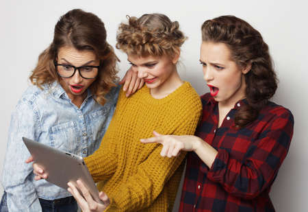 Three hipster female friends use digital tabletの写真素材
