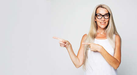 middle age woman smiling cheerfully, feeling happy and pointing to the side and upwards, showing objectの写真素材