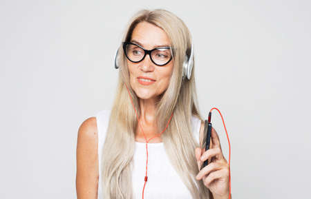 happy senior woman with long white hair listening to music with headphonesの写真素材
