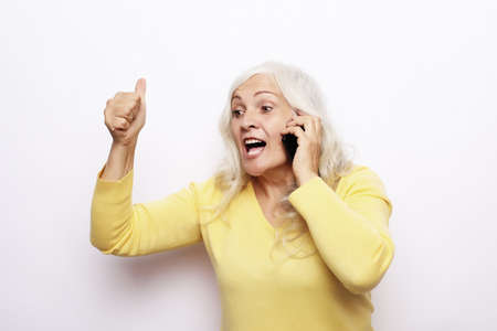 Photo of crazy ecstatic old woman use smartphone impressed social media like feedback win raise fists scream yes isolated over white backgroundの写真素材