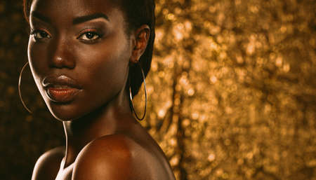 Vogue style close-up portrait of beautiful black woman. Portrait over gold background.