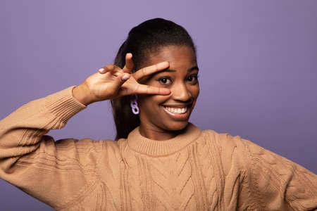 Young beautiful African American woman wearing beige casual sweater showing and pointing up with...