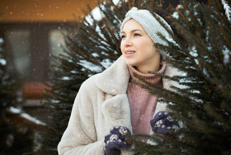 Lovely woman in winter clothes next to the Christmas tree, winter, christmas market.の写真素材