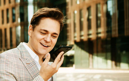 Young business man talking on phone near modern office building.の写真素材