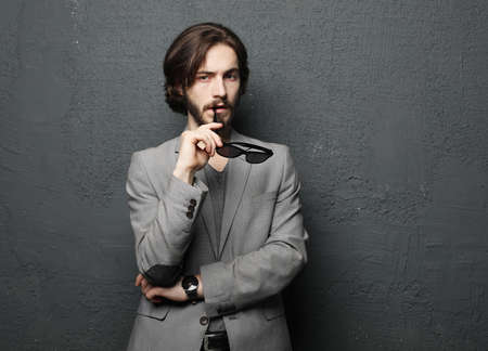 Portrait of a young handsome man wearing sunglasses on gray background. Studio fashion portrait.