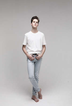 Young Male Model wearing white t-shirt and jeans. Portrait over gray background.