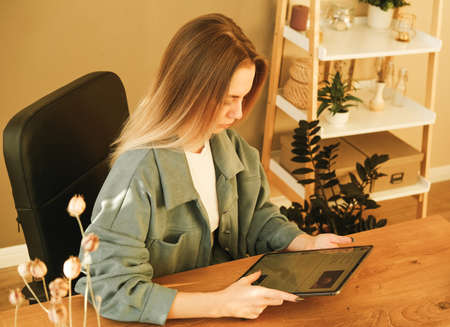 Image of young beautiful woman smiling while working with tablet pc in office