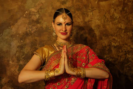 beautiful Indian girl in a greeting pose to Namaste hands. India woman in traditional saree.
