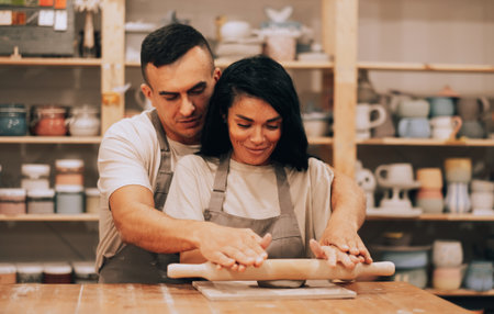 Couple in love working together on potter wheel in craft studio workshop. Lifestyle cocnept.