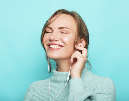 Cheerful young blond woman wearing casual Listen music with earphonesの写真素材