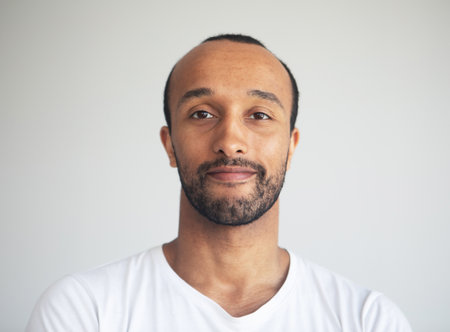 A young unshaven smiling man on a light gray background. African American. close-up portrait.の写真素材