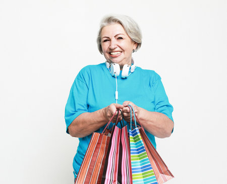 Lifestyle, shopping and old people concept: Happy mature woman with shopping bags isolated on white backgroundの写真素材