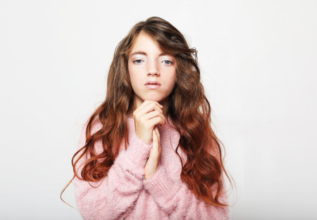 People, childhood and fashion concept: cute little girl child wearing pink sweater over white...