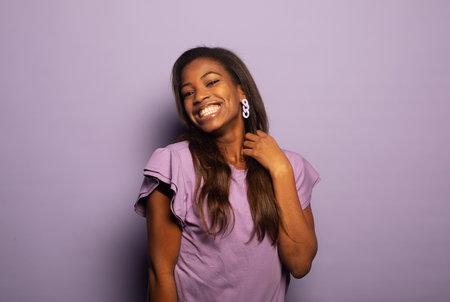 Charming young afro american woman smiles happy over purple backgroundの写真素材