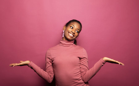 Young black woman feeling excited, shouting OMG or WOW, expressing emotion of joy on pink studio background.の写真素材