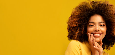 Positive dark skinned woman isolated over yellow background.の写真素材