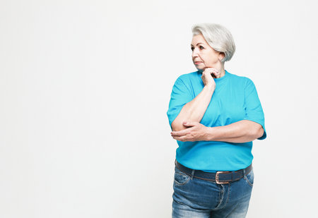 old people and decision making concept - portrait of senior woman in blue tshirt thinking over white backgroundの写真素材