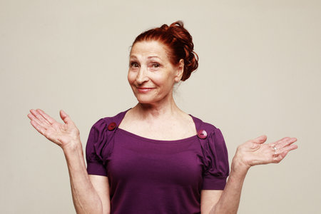 A cheerful happy old woman laughs and rejoices. Portrait over gray background.