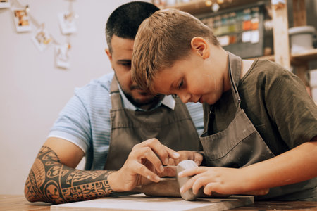 Pottering with son. Confident young man and little boy making ceramic pot on the pottery classの写真素材