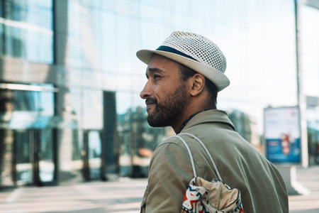 portrait of serious young African man wearinghat and backpack with serious expression in the city, summer dayの写真素材