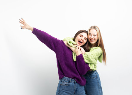 Two cheerful young women hugging and having fun together over white background, the concept of friendship and youth. lifestyle and people concept.の写真素材