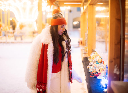 Charming young woman at the Christmas market next to the New Year tree. Winter time.
