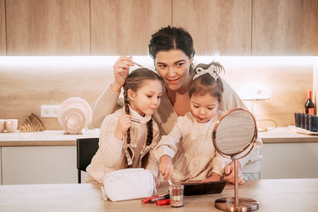 Two little girls sisters play with their mother using cosmetics. makeup game. happy time at home. lifestyle concept.の写真素材