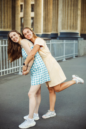 Young female friends outdoors in the city. They are sitting while talking at sunset in summer. lifestyle concept.の写真素材