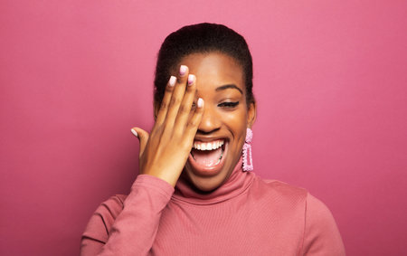 Portarit of young beautiful African-American young woman smiling broadly and close eye over pink background. Lifestyle and people concept.の写真素材