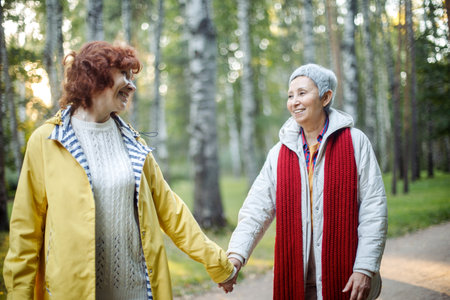 Cheerful pensioner female friends tallking and laughing in the autumn park.の写真素材