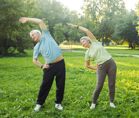 Yoga at park. Senior family couple exercising outdoors.の写真素材