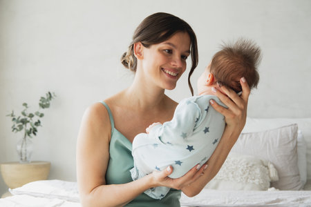 Loving mom caring of her newborn baby at home. Bright portrait of happy mum holding sleeping infant child on hands. Mother hugging her little 1 month old son.の写真素材