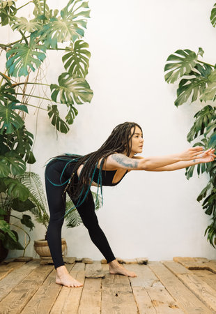 A young woman with braids does sports. The trainer does yoga asana exercises. Fitness at home with...