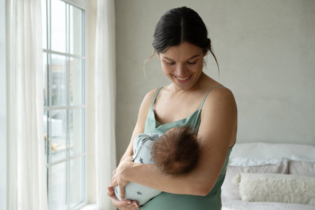 Loving mom caring of her newborn baby at home. Lifestyle and family concept.