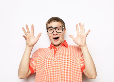 young handsome man wearing eyeglasses with surprised emotions on his face a gray backgroundの写真素材