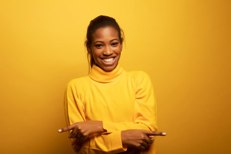 Close up portrait of beautiful young African woman laughing over yellow background, lifestyle and people concept.の写真素材