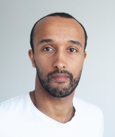 A young unshaven man on a light gray background. Mixed race handsome male model. Close up portrait.の写真素材