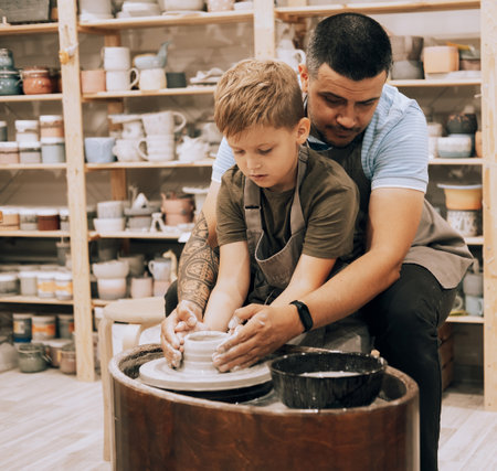 Confident young man and little boy making ceramic pot on the pottery class. Lifestyle and people concept.の写真素材