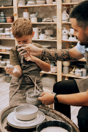Confident young man and little boy making ceramic pot on the pottery class. Lifestyle and people concept.の写真素材