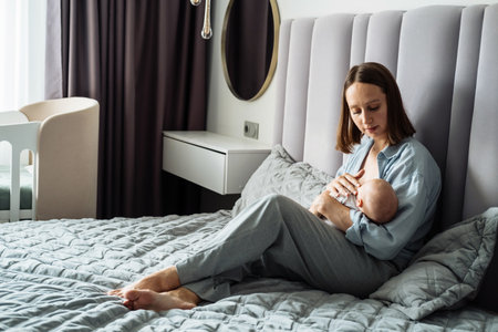 Home portrait of a newborn baby with mother on the bed.