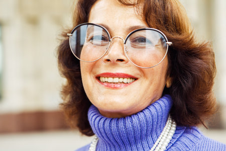 A cheerful elderly lady in a purple sweater is relaxing on the street on a summer day. Lifestyle and people concept.の写真素材