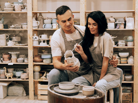 A young smiling couple works in a pottery workshop. Painting a vase. The concept of hobbies and lifestyle.の写真素材