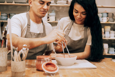 A young smiling couple works in a pottery workshop. Painting a vase. The concept of hobbies and lifestyle.の写真素材
