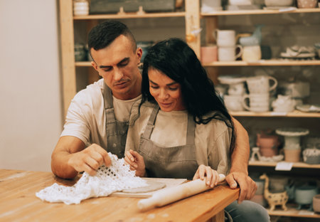 A young smiling couple is engaged in creativity in a pottery workshopの写真素材