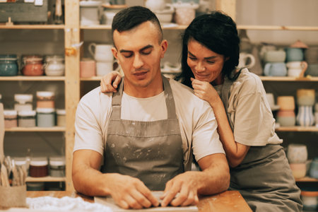 A young smiling couple is engaged in creativity in a pottery workshopの写真素材
