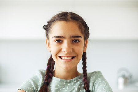 Charming smiling ten-year-old girl with pigtails, close-up portrait at home.の写真素材
