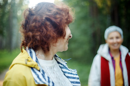 Cheerful pensioner female friends tallking and laughing in the autumn park. Lifestyle and old people concept.の写真素材
