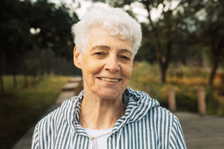 Pretty elderly curly woman smiling in the park